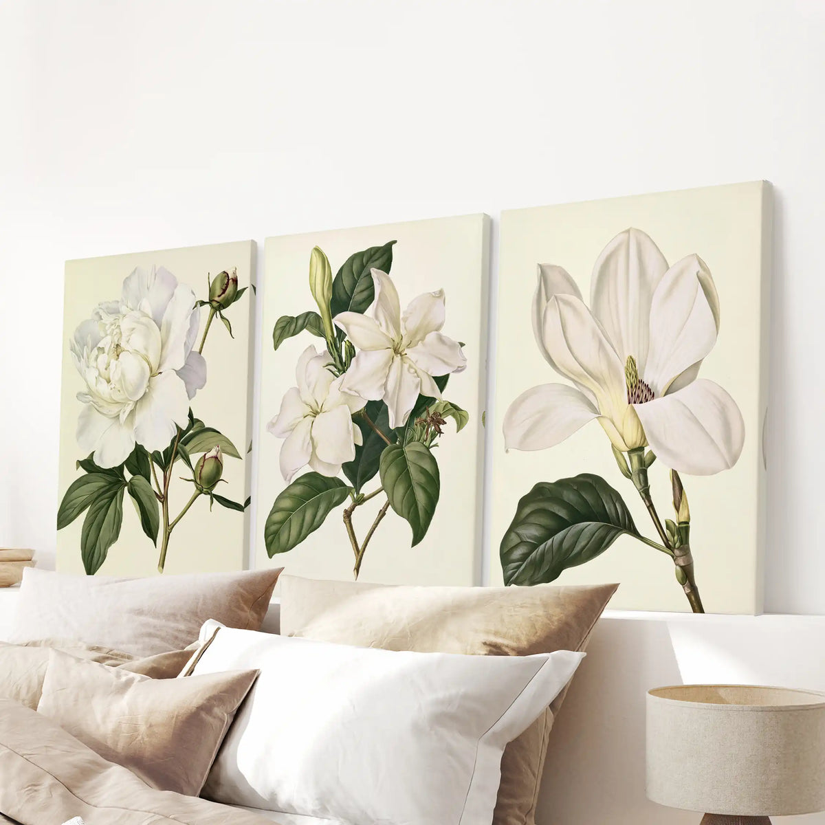 White flowers with green leaves fill three canvases above a bed.