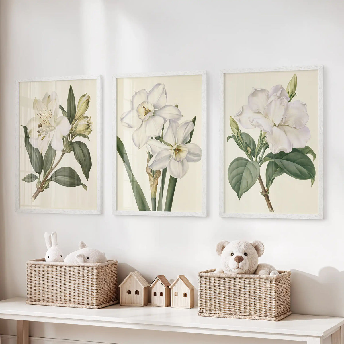 A central narcissus study and two leafy white flower prints hang above toy baskets in three white frames.