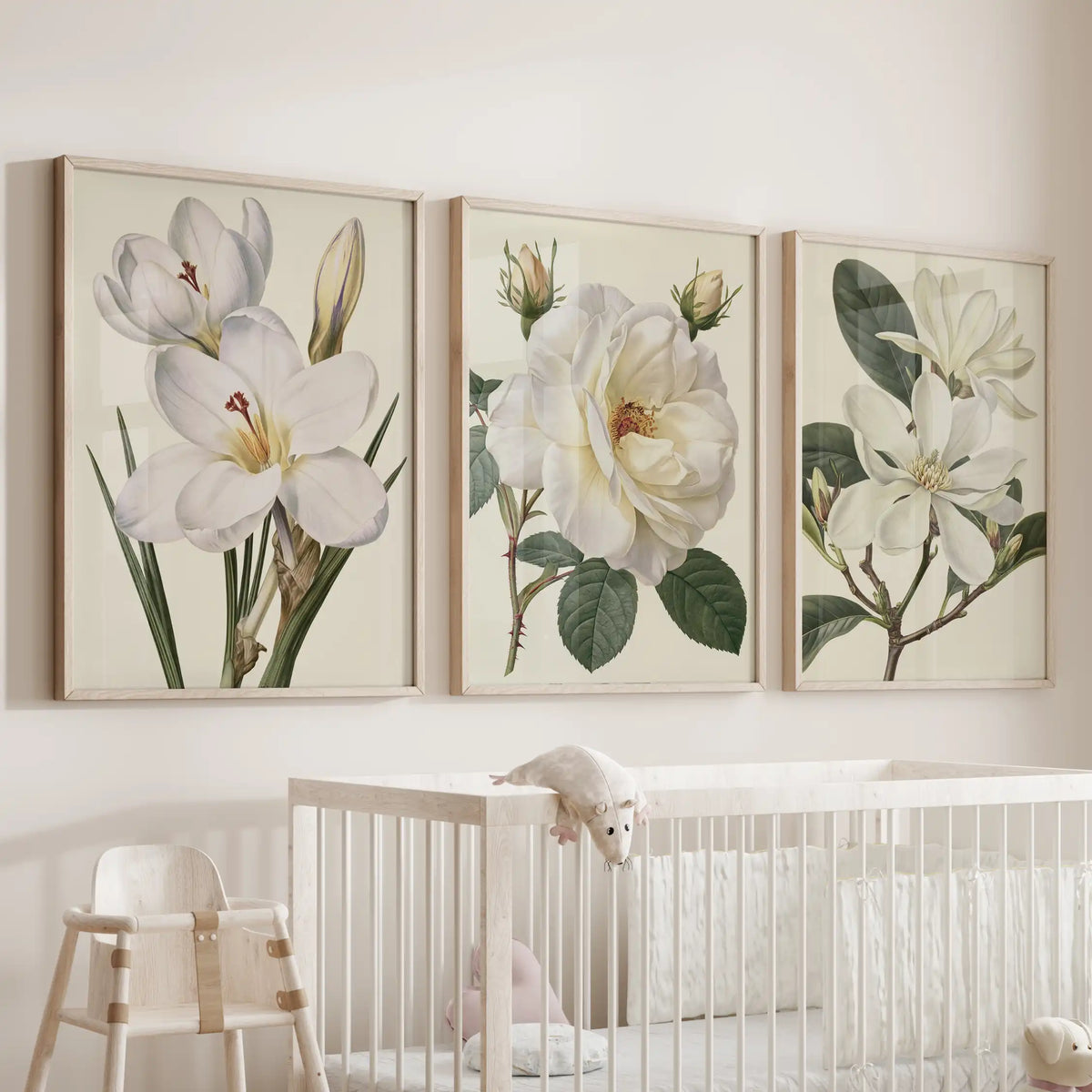 White botanical flowers fill three oak-framed prints above a nursery crib.