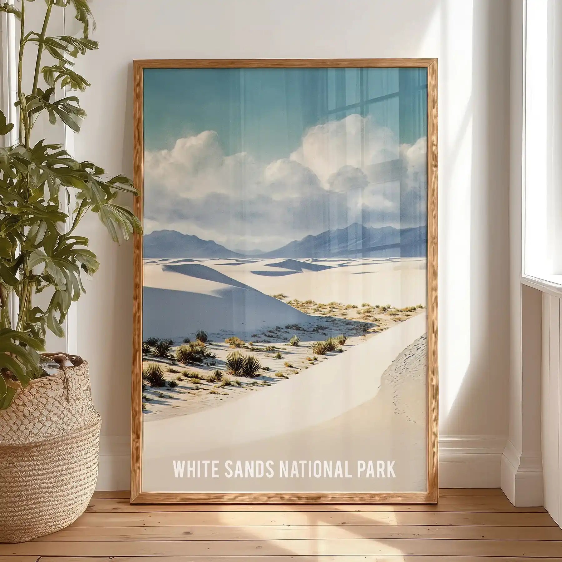 Standalone desert landscape artwork in a natural wood frame rests on the bedroom floor, lending an organic warmth to the space.