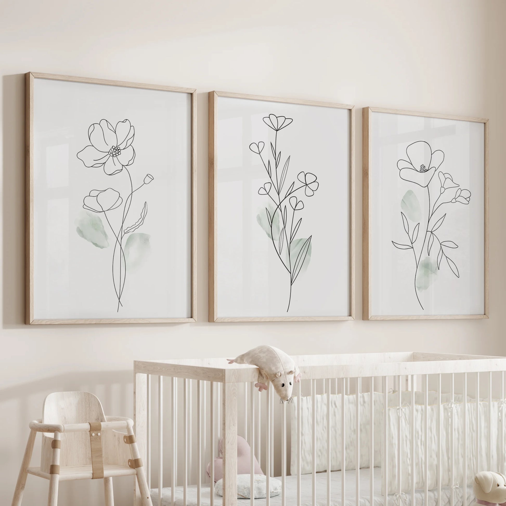 Black line flower illustrations, a wall art set of three in wood frames, watch over the nursery bassinet with gentle botanical outlines and calming simplicity.