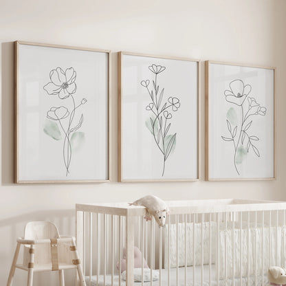 Black line flower illustrations, a wall art set of three in wood frames, watch over the nursery bassinet with gentle botanical outlines and calming simplicity.