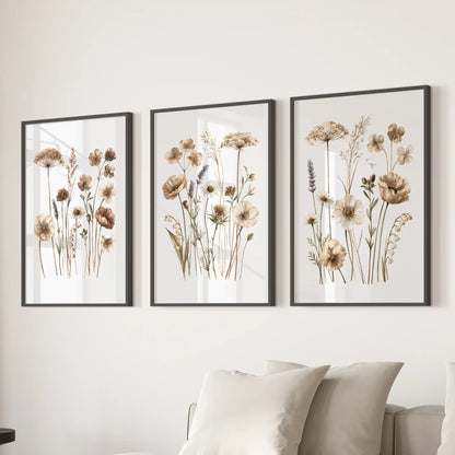 Beige meadow flower prints in black frames, a set of three above a sofa.