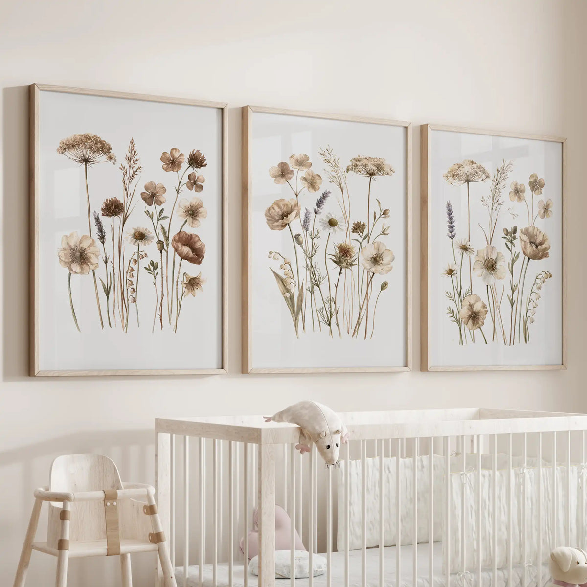 Neutral wildflower wall art in three oak frames above a nursery crib.