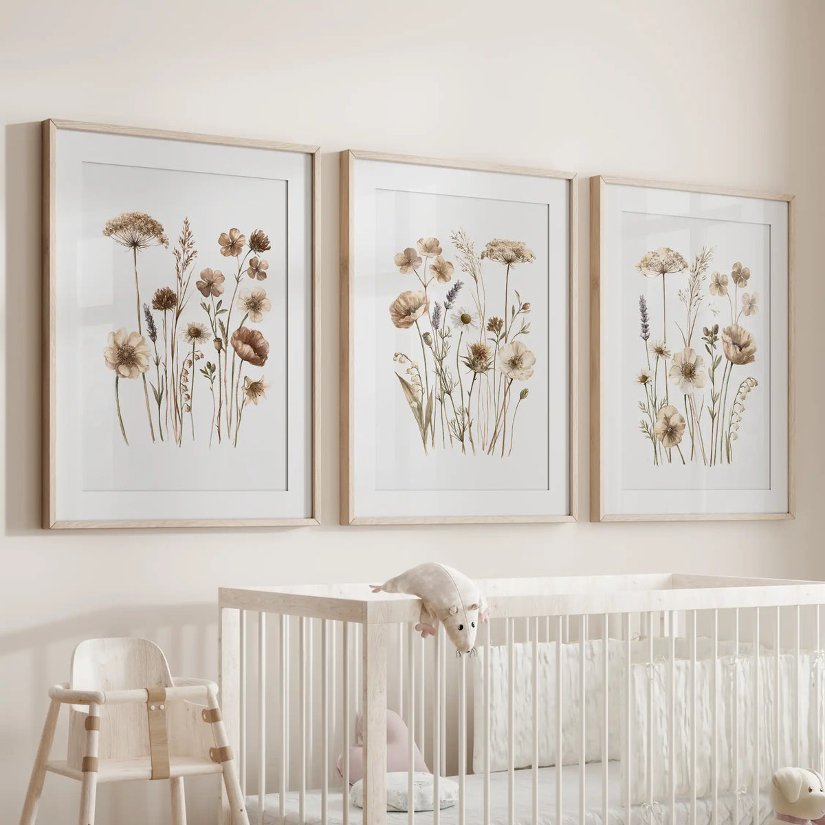 Beige meadow flower prints in oak frames with white mats, a set of three above a crib.