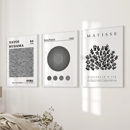 Three white-framed geometric posters bring crisp Bauhaus balance to the bedroom wall beside the bed, adding sharp modern detail.